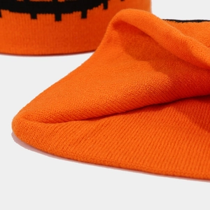 Close-up of orange knitted beanie featuring black pixelated Halloween pumpkin patterns