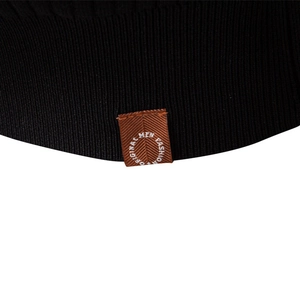 Close-up of black knitted rib texture with brown original men fashion woven label detail