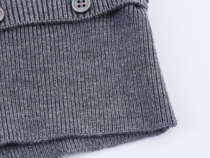 Gros plan sur la maille côtelée et le bouton nacré foncé du pull décontracté gris