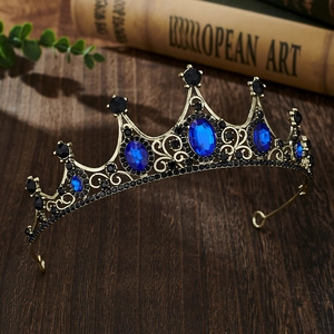 Close-up of vintage bronze tiara with blue gemstones and black rhinestones on dark wood