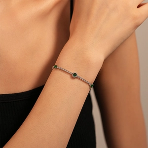 Detail of luxury geometric bracelet featuring round green stones and sparkling pavé crystals