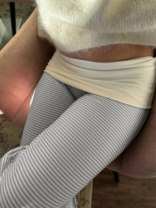 Detail of high-waist striped trousers with white knit sweater texture and fabric pattern