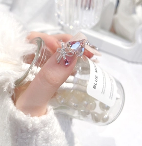 Macro shot of press-on nails featuring a giant heart crystal and silver glitter bow