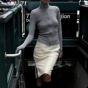 Pull en maille gris zippé chic et jupe beige fendue portés dans le métro de New York