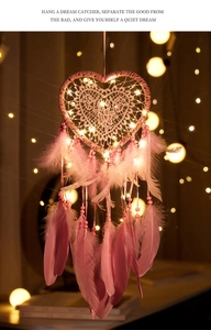 Close-up of pink heart dream catcher with glowing LED lights and soft feathers