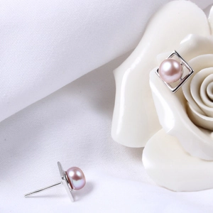 Detail view of round pink freshwater pearl earrings set in square silver frames