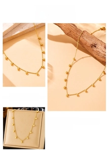Detailed view of a gold chain necklace with polished beads on a minimalist display