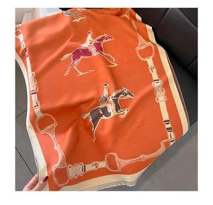 Detail view of thick orange horse pattern scarf with equestrian prints and soft fringe tassels