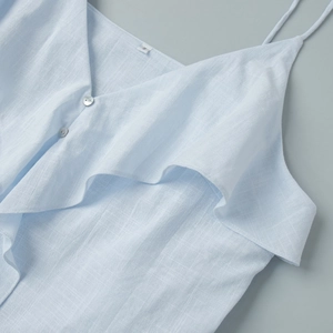 Detailed view of blue cotton top featuring ruffled V-neckline and small white buttons