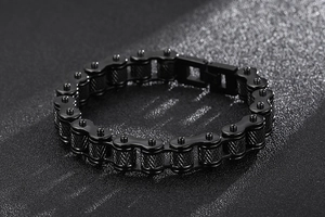 Macro detail of black bike chain bracelet with textured metal rollers in hip-hop style