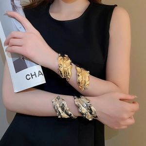 Detail of metallic leaf-shaped open arm cuffs in gold and silver with textured veins