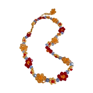Collier de perles fait main avec fleurs en cristal et perles dorées sur fond blanc neutre