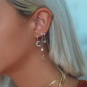 Close-up of S925 silver star and moon earrings with light blue opals on female model