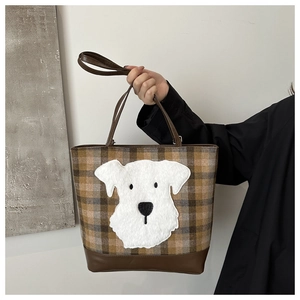 Close-up of brown plaid wool tote bag with plush white dog patch and leather handles