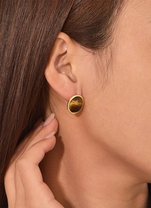 Close-up of a model wearing a round brown tiger eye stud earring with gold plating