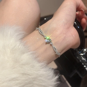 Detail of silver heart bracelet with zircon stones worn on wrist against soft fur background