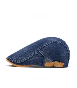 Close-up of denim beret with adjustable brown strap and antique bronze metal buckle