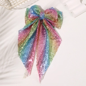 Detail of oversized sequined rainbow bow hair clip with long colorful streamers