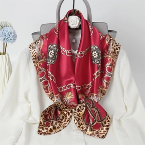 Detail of red silk scarf with gold chain and leopard print styled on a white shirt