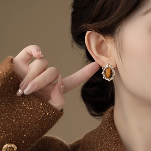 Elegant gold oval tiger eye stud earrings with vintage lace design worn by model