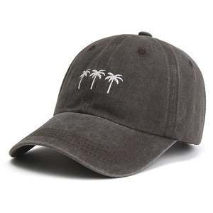 Macro shot of white embroidered palm trees on a charcoal grey washed cotton baseball cap