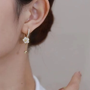 Elegant gold flower earrings with white crystals and yellow center stone on model