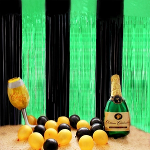 Green and black foil fringe curtain backdrop with champagne balloons for party decor