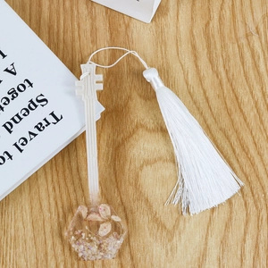 Détail d'un marque-page en résine en forme de guitare avec fleurs séchées et pompon blanc