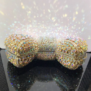 Detailed close-up of bow clutch bag with colorful rhinestones on gold metal base