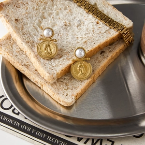 Detail of vintage gold coin earrings with pearl accents displayed on a breakfast tray