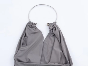 Detail of grey knitted halter top featuring a stylish metal ring neckline design