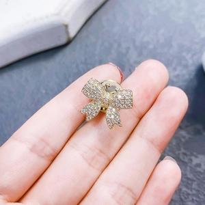 Macro shot of a small golden bow brooch with sparkling crystals held by a hand