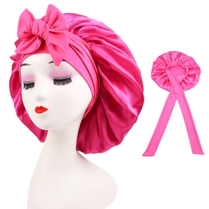 Detail of hot pink satin sleep cap featuring large bow decoration and long elastic ties