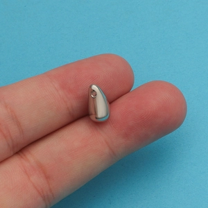 Macro view of a small silver teardrop pendant held between fingers for size reference