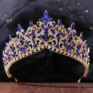 Close-up of golden bridal crown with blue crystals and sparkling diamonds on dark fabric