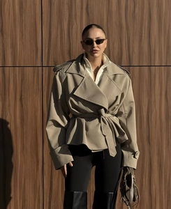 Detailed close-up of khaki short trench coat with wide lapels and matching belt waist
