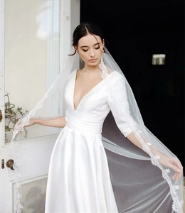 Elegant white satin bridal gown with V-neck, three-quarter sleeves and lace veil