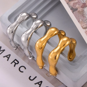 Modern wavy C-shape earrings in gold and silver finish on a minimalist display