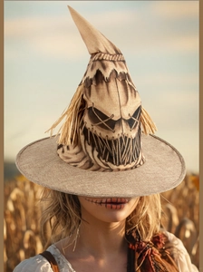 Detailed view of burlap scarecrow witch hat with straw decor in a golden wheat field