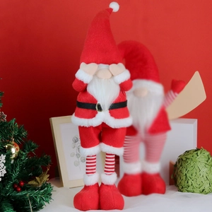 Close-up of plush Christmas gnome with long beard and striped legs in festive setting