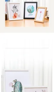 Minimalist wooden photo frame set with botanical prints on a sunlit wooden desk
