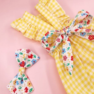 Detailed view of yellow plaid dog dress with floral bows and elegant ruffled edges