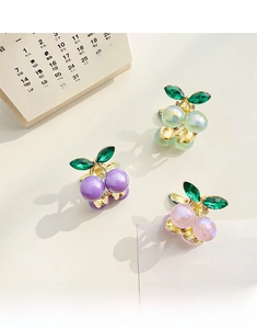 Detailed close-up of three sweet cherry hair clips in purple, pink and teal pearlescent finish