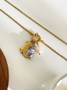 Macro detail of retro golden boot charm with blue porcelain beads and baroque pearl necklace
