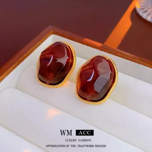 Macro shot of vintage tiger eye geometric earrings with braided gold frames on white velvet
