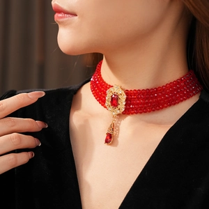 Detail of vintage red bead multilayer choker with ornate gold pendant and ruby-like stone
