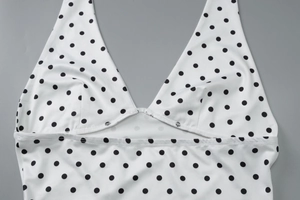 Close-up of white polka dot top showing deep V-neckline and high-quality fabric stitching