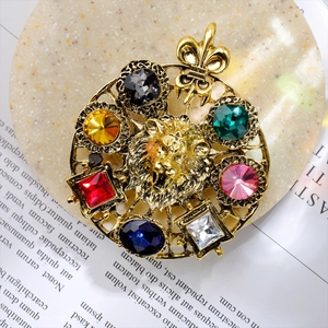 Detail of vintage gold lion head brooch with multi-colored gemstones on a stone base