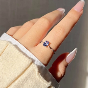 Detail of a link chain ring featuring a deep blue oval zircon on a model's finger