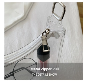 Macro view of a silver metal zipper pull on a transparent PVC jelly shoulder bag